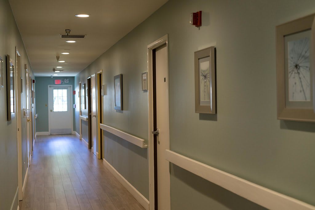 A well-lit hallway with multiple doors and framed pictures on the walls.