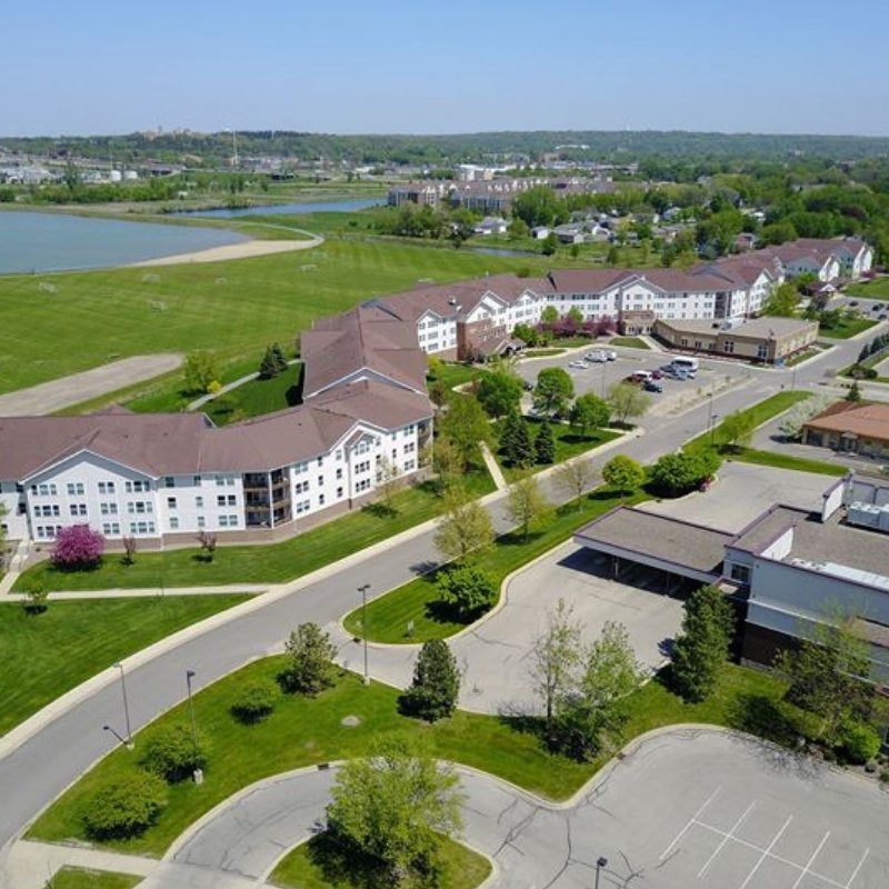 Aerial view of a residential suburb with apartments, greenery, and a nearby lake.