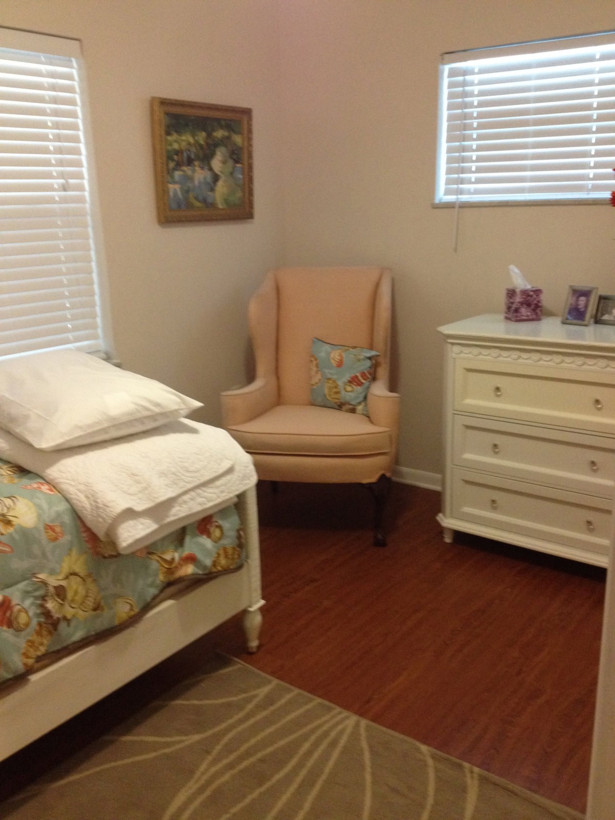 A cozy bedroom with a bed, armchair, and dresser.