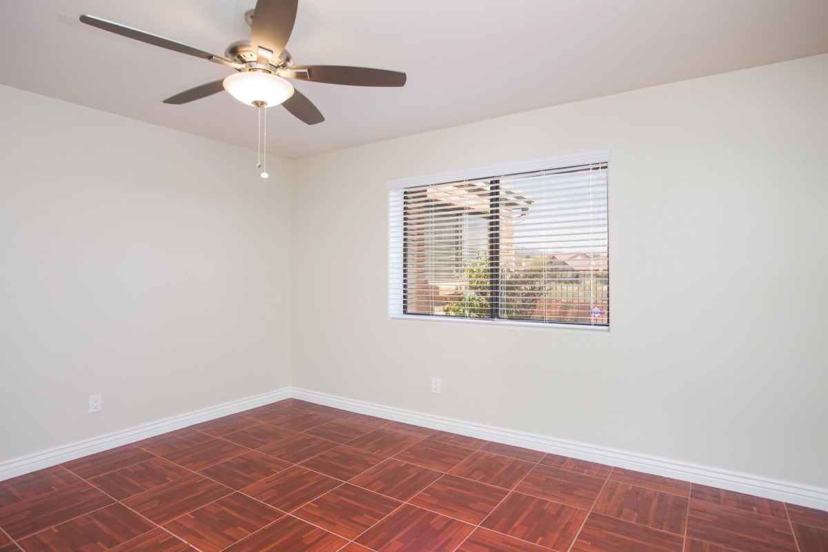 An empty room with a ceiling fan and tiled flooring.