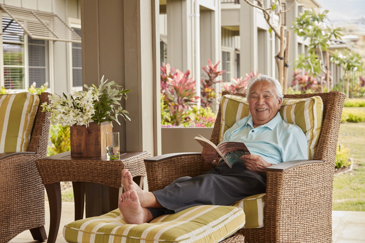 An older person enjoying a book while relaxing on an outdoor chair.