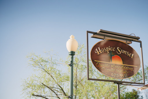 A beautifully lit sign for 'Hospice Springs' against a clear blue sky.