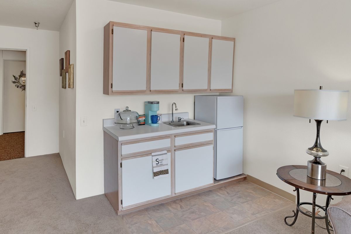 A small kitchen area featuring a sink, upper and lower cabinets, and a refrigerator.
