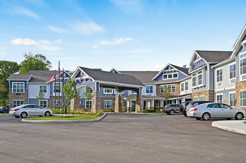 A modern residential building with a parking area and flags displayed.