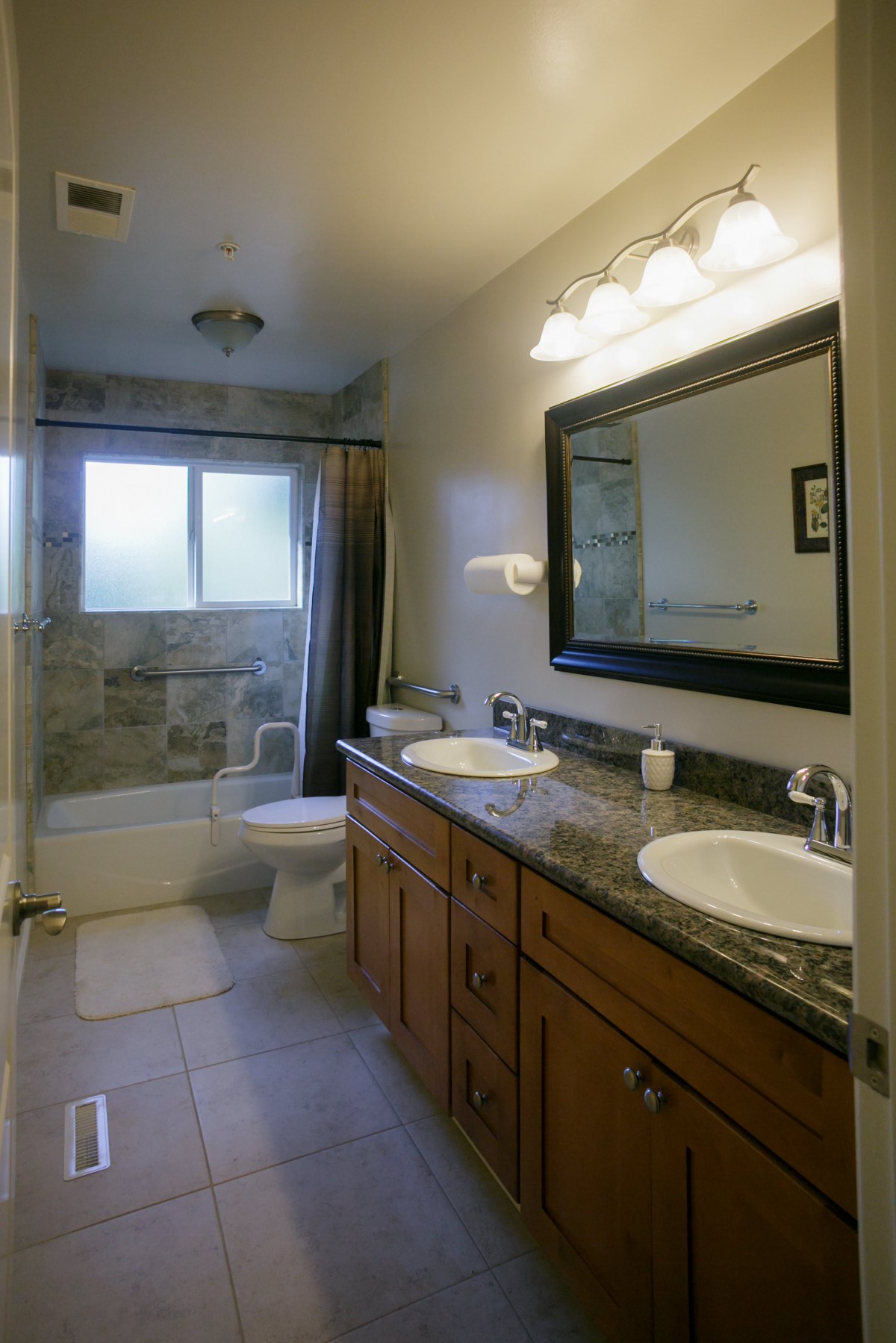 A modern bathroom featuring double sinks, a large mirror, and a bathtub with a shower curtain.