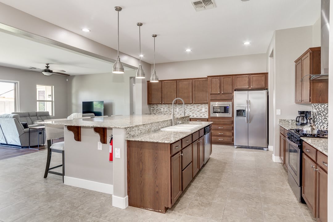 A modern kitchen with wooden cabinets, granite countertops, and stainless steel appliances.