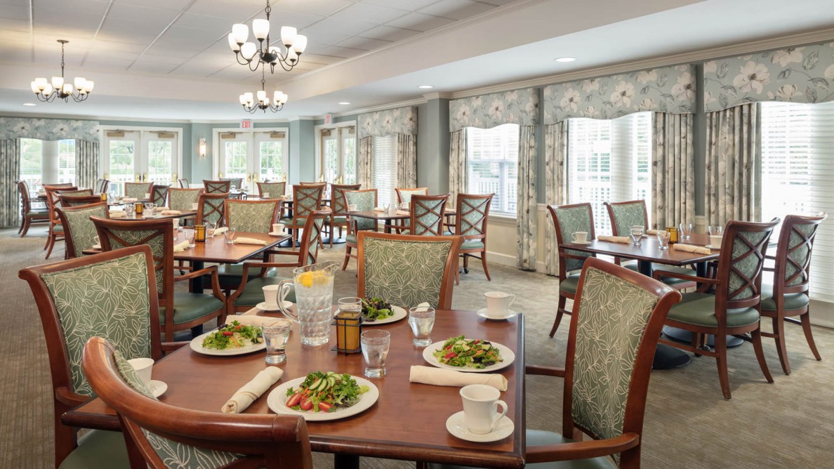 A well-furnished dining area with tables set for meals, featuring elegant decor and natural light.