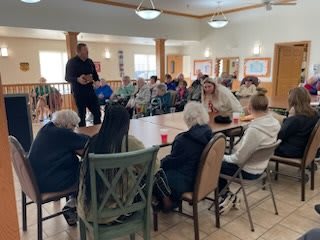A community gathering with people seated around a table in a bright room.
