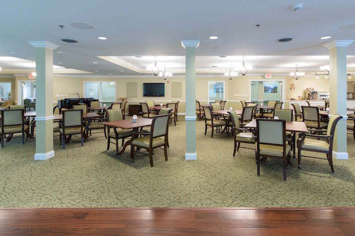A spacious dining room with multiple tables and chairs, well-lit and designed for gatherings.