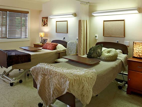 A hospital room with two beds and privacy curtains.