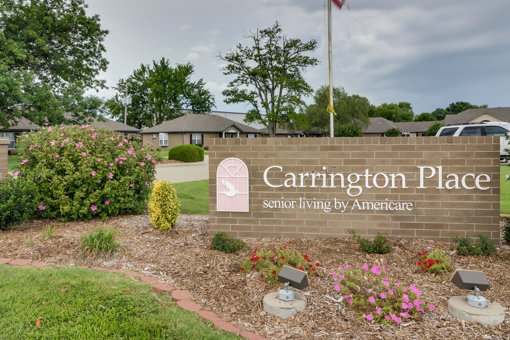 A brick sign for Carrington II, surrounded by landscaping and under a cloudy sky.