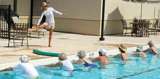 A water aerobics class for seniors, led by an instructor by the pool.