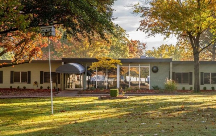 A mid-century modern house surrounded by autumn foliage.