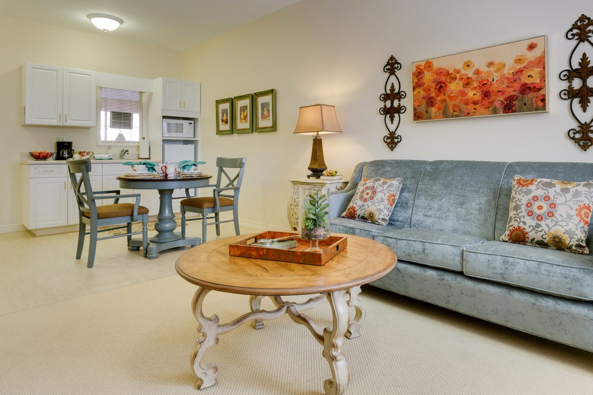 A cozy living room with a vintage-style coffee table, a comfortable sofa, and a small dining area in the background.