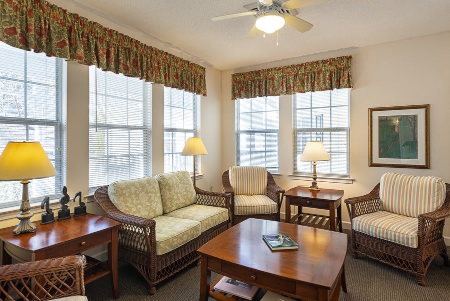 A cozy living room with wicker furniture and large windows.
