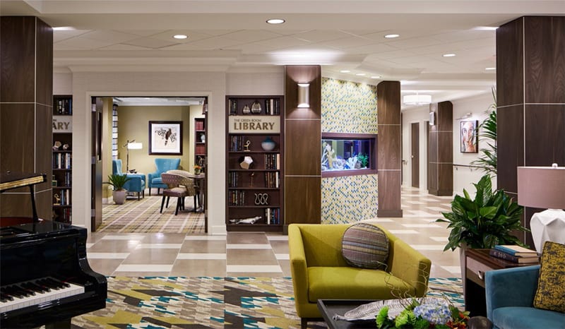A modern hotel lobby featuring stylish furniture, a library section, and elegant decor.