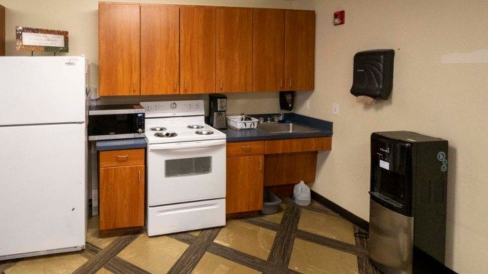 A small kitchen space with a stove, microwave, and wooden cabinets.