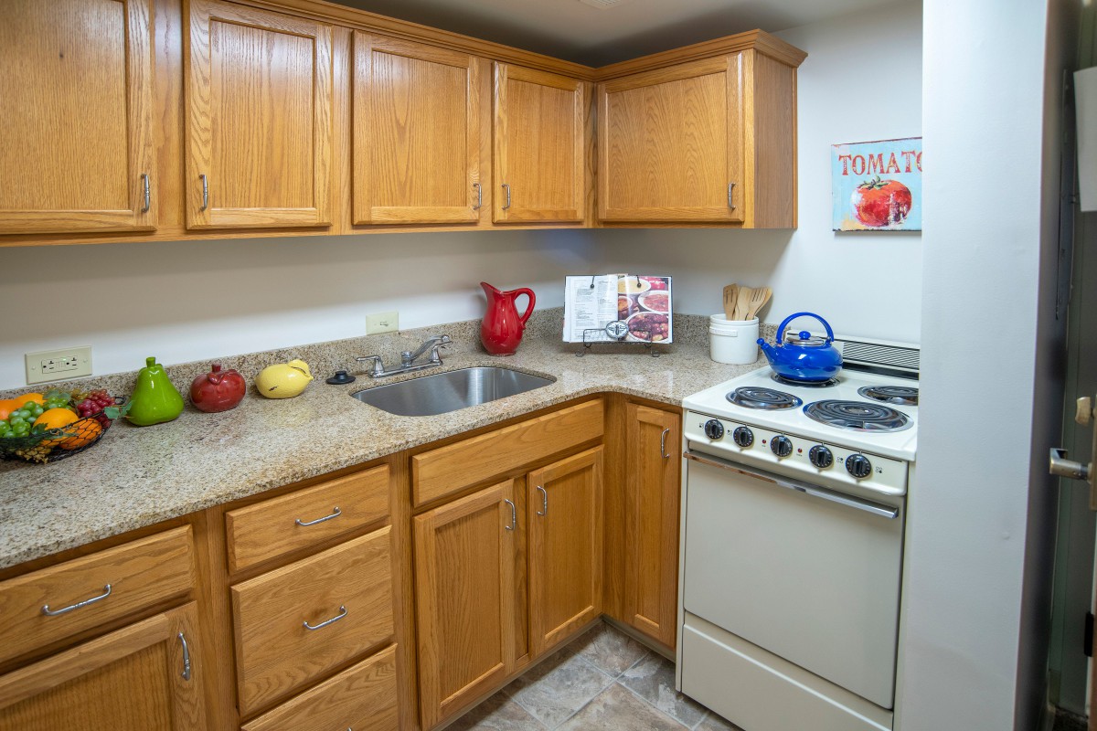 A compact kitchen with wooden cabinets, a stove, and a sink.