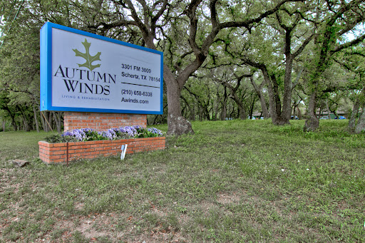 A welcoming sign for Autumn Winds, surrounded by lush greenery and trees.