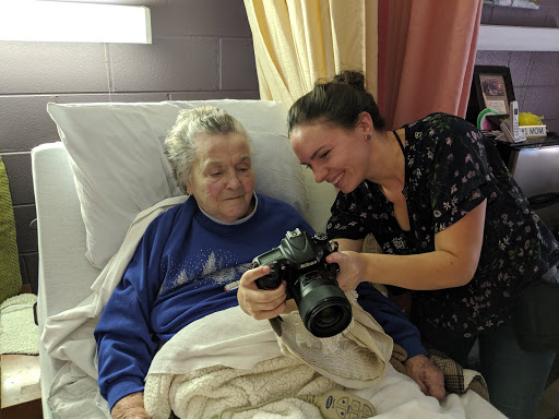 A warm moment shared between a caregiver and an elderly patient as they look at photos together.