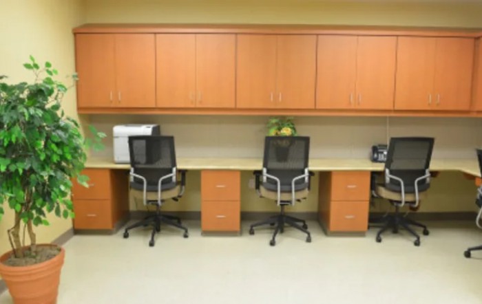 An organized office workspace with three chairs and desks.