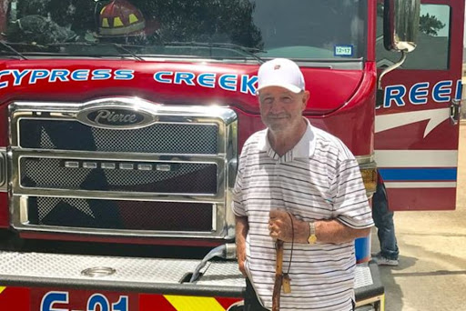 A man poses in front of a fire truck, showcasing community pride and service.
