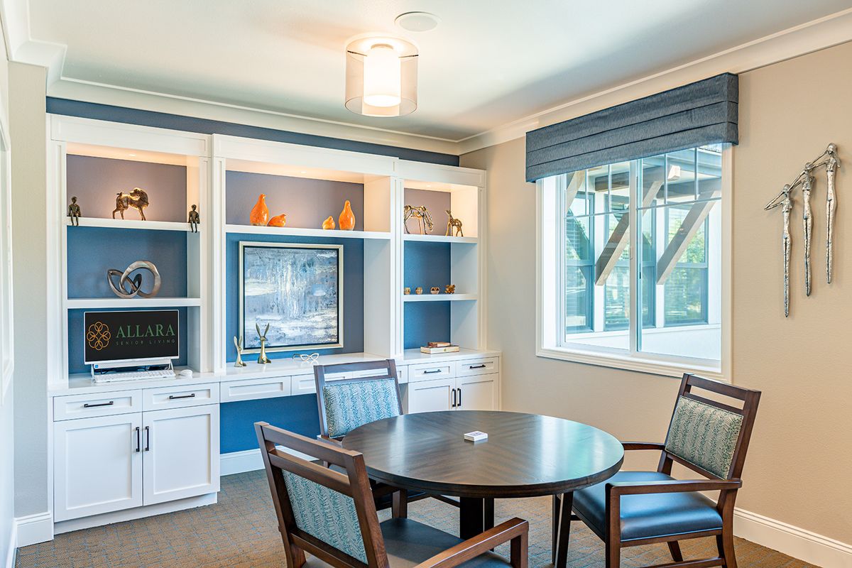 A bright meeting room with a round table, chairs, and built-in bookshelves.