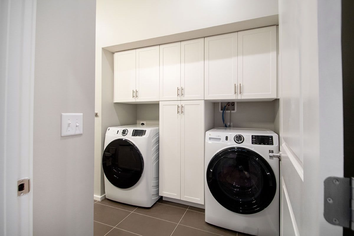 A modern laundry room with a washing machine, dryer, and ample cabinetry.