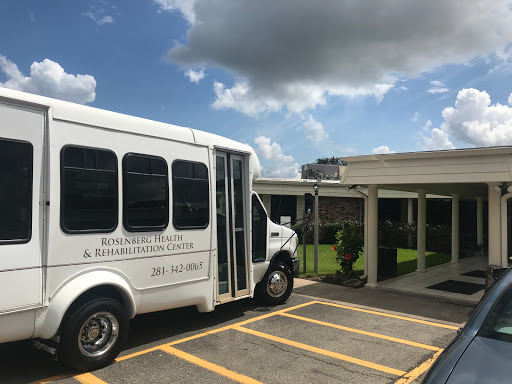 A white transportation bus parked outside a building under a partly cloudy sky.