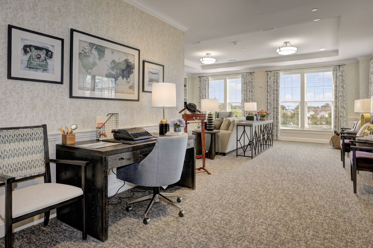 A spacious, well-lit office with a desk, chair, and artwork adorning the walls.