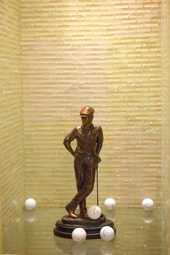 A bronze statue of a person leaning with a cane, showcased in a display case.