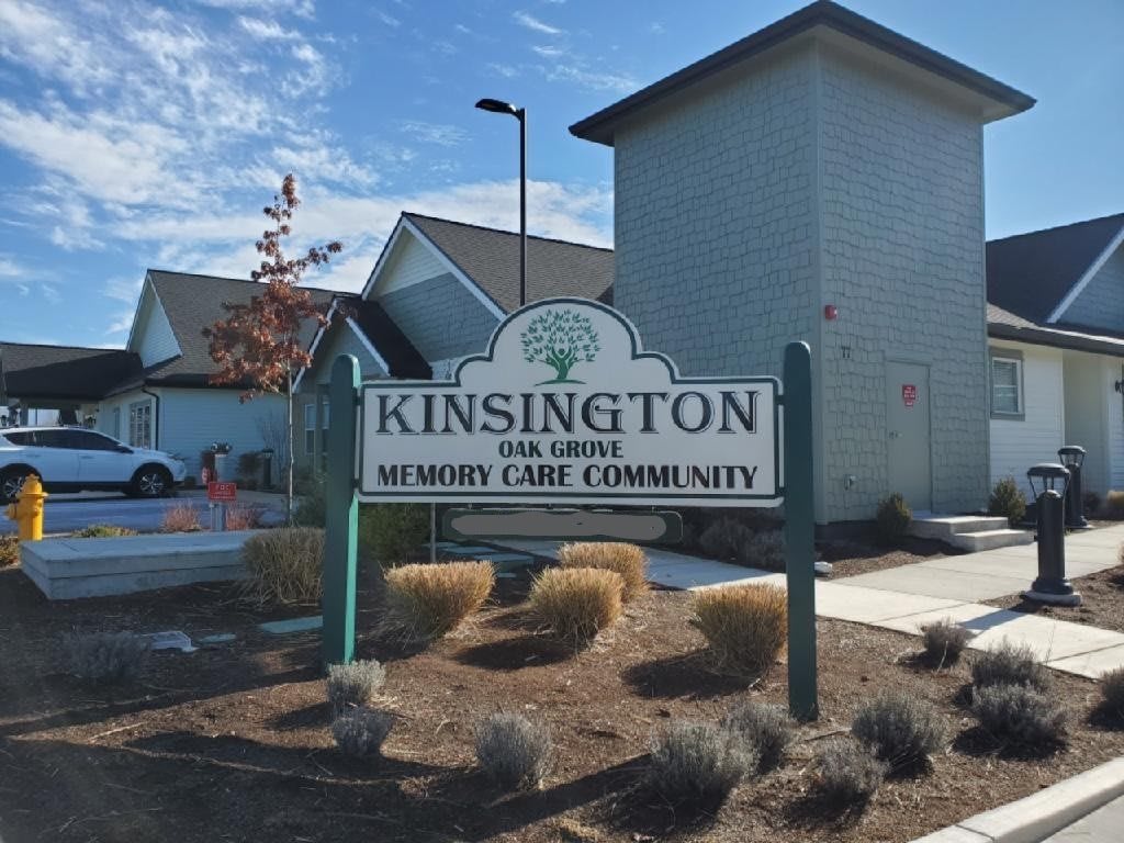 Sign for Kinsington Oak Grove Senior Care Community in front of residential buildings.