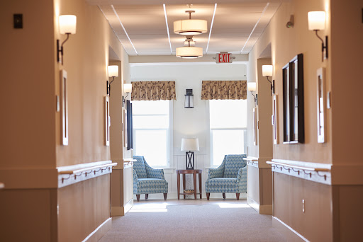 A bright and inviting hallway featuring comfortable seating areas and large windows.