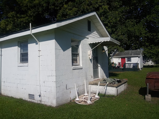 A small white house with a porch and grassy yard, showcasing a simple rural lifestyle.