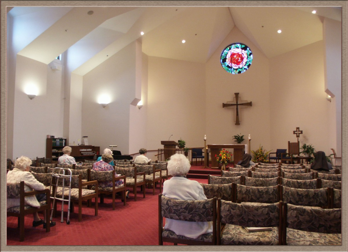 A church interior with people seated and a cross at the front.