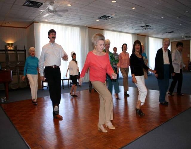 A group of seniors participating in a line dancing class indoors.