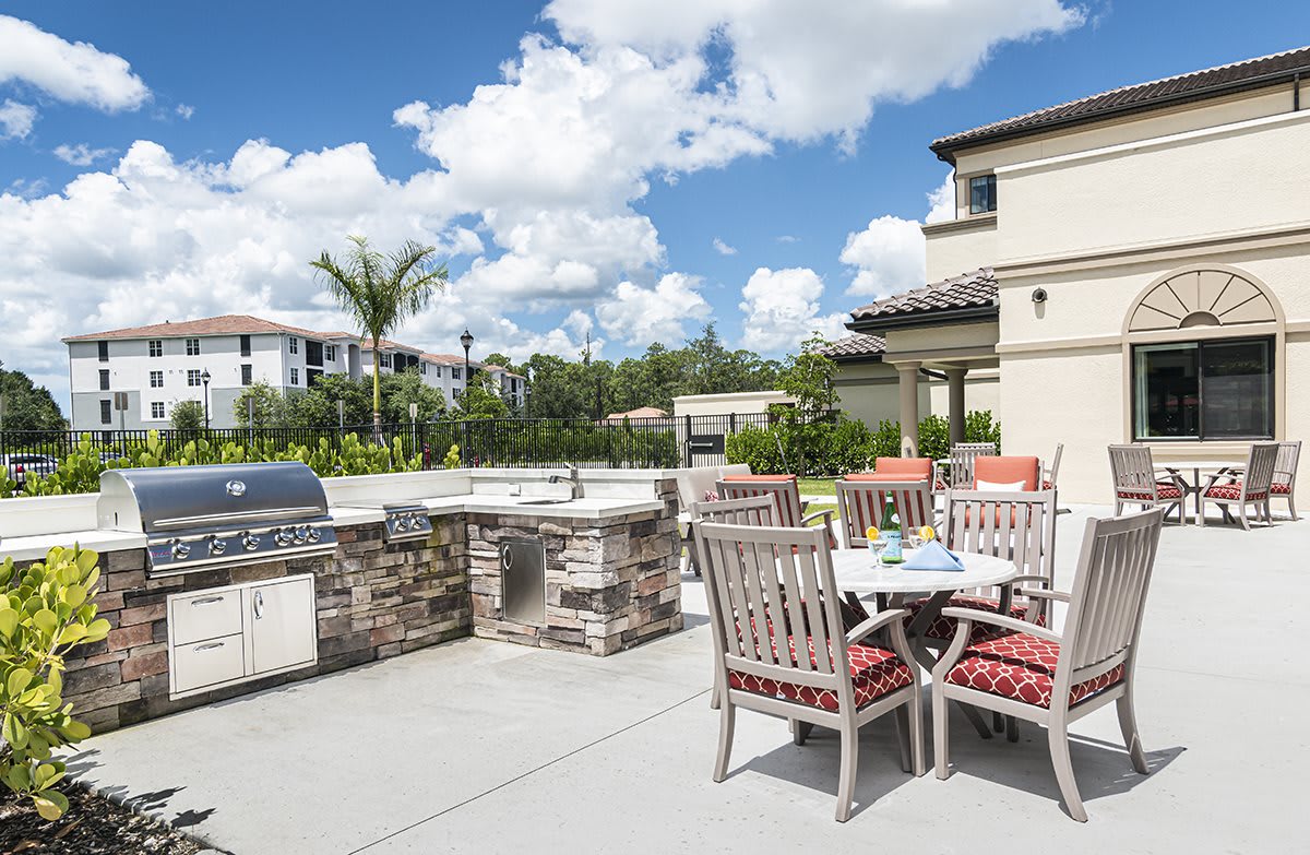 A spacious outdoor patio with a barbecue grill and dining area set against a sunny backdrop.