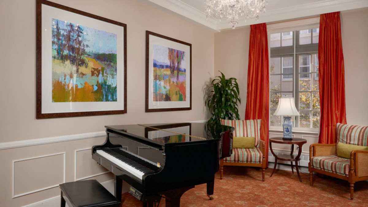A stylish living room featuring a grand piano, colorful artwork, and elegant decor.