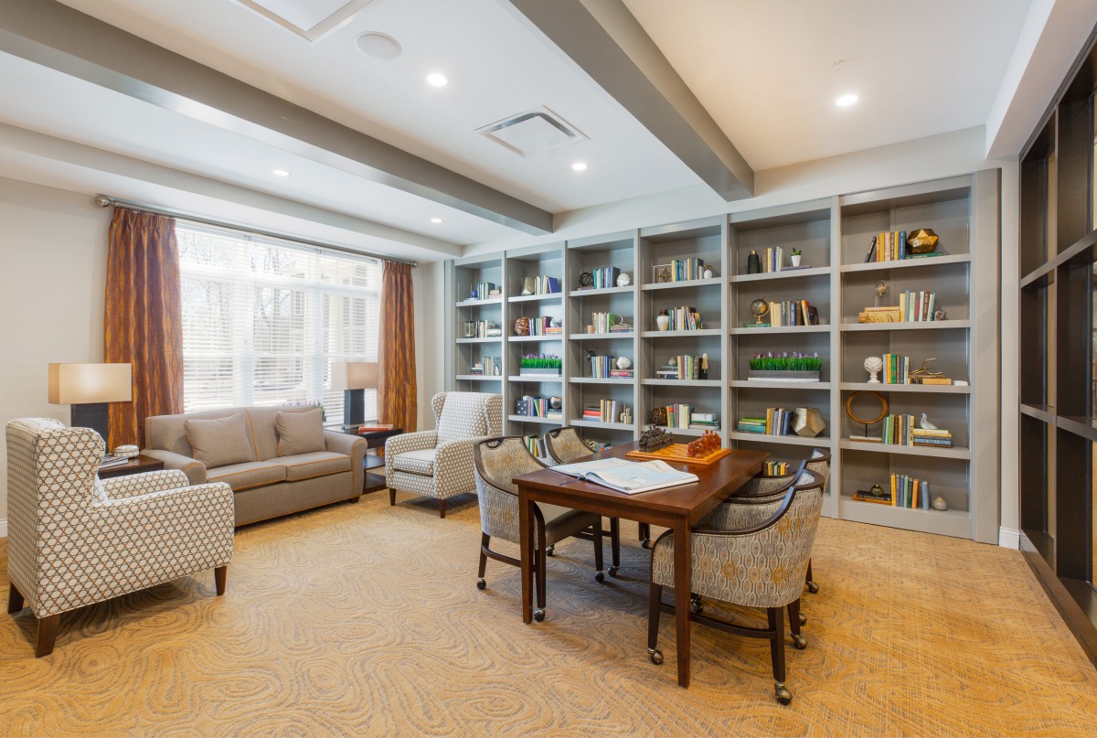 A modern library with bookshelves, a seating area, and a table with chairs.
