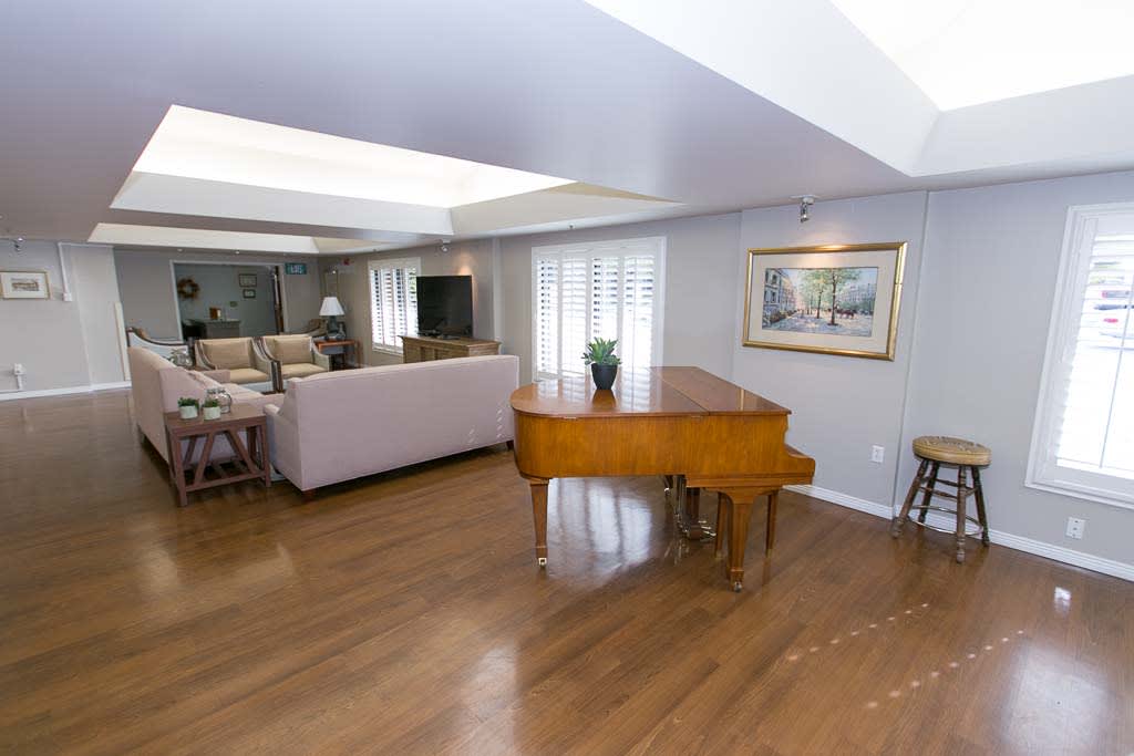 A spacious living room featuring a grand piano, comfortable seating, and elegant decor.