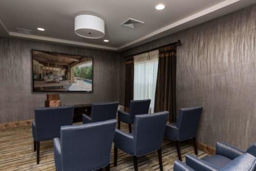 A small, well-furnished meeting room with blue chairs and a large painting on the wall.