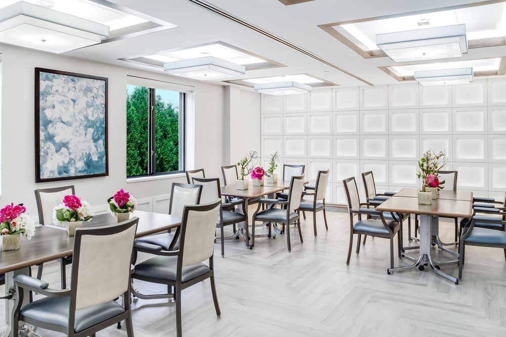 A modern dining area with elegantly arranged tables and chairs, adorned with flowers and art.