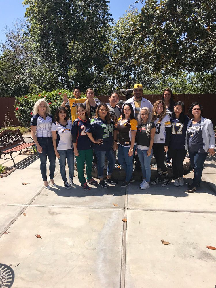 A group of people posing for a photo together outdoors on a sunny day.
