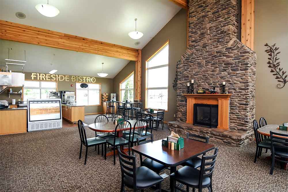 A cozy dining area with a stone fireplace and wooden furniture.