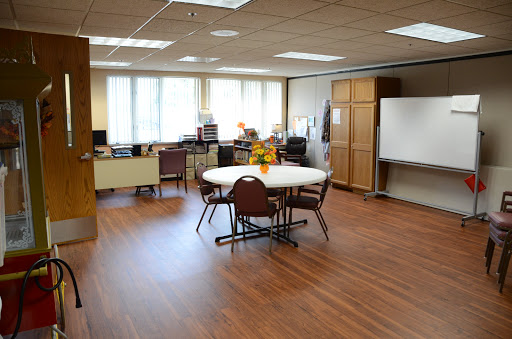A well-lit office meeting room featuring a round table and chairs, suitable for group discussions.