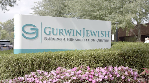 Entrance sign of the Gurwin Jewish Nursing & Rehabilitation Center surrounded by flowers.