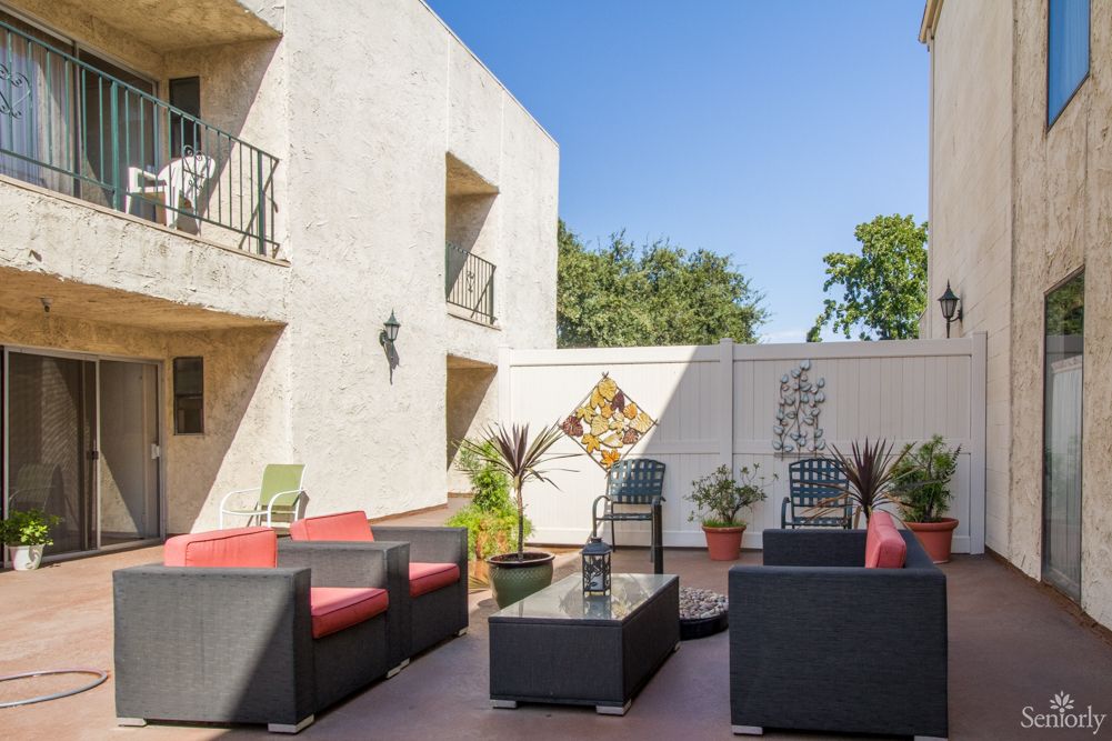 A modern outdoor patio with comfortable seating and decorative plants on a sunny day.
