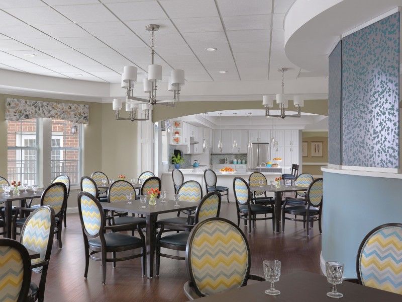 A modern dining area with stylish chairs and tables, featuring elegant lighting and a neutral color palette.