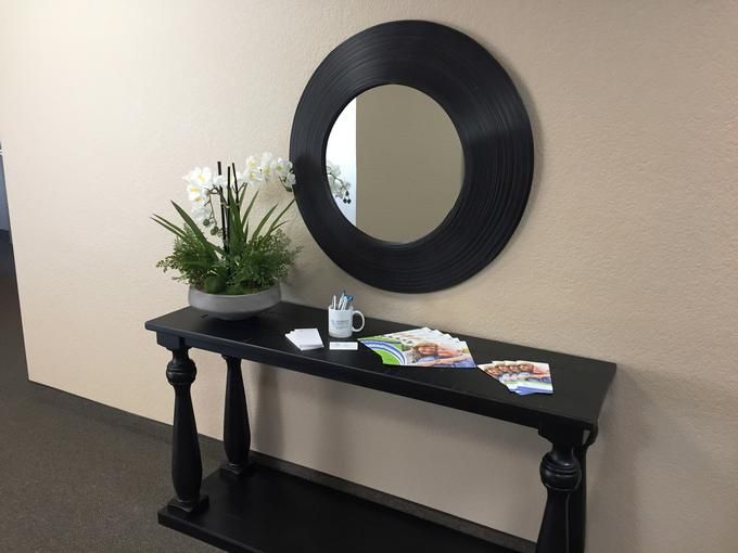 A stylish console table with a decorative mirror and a plant arrangement in a modern interior setting.