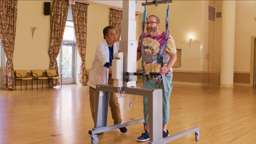 A person receiving support with a walking aid during rehabilitation therapy.
